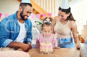 Blow out your candles. a little girl celebrating a birthday with her parents at home.