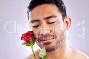 Wild but beautiful. Studio shot of a handsome young man posing with a red rose.