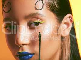 Jump on this new make up trend. Studio shot of a beautiful young woman holding a mascara brush against her face.