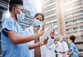 Technology changes the way the medical field operates. two young female doctors using a digital tablet in the city.