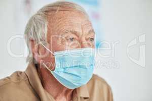 I really need to think about this. a senior man sitting alone and wearing a face mask in the clinic during his consult.