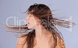 You trendy Im wholesome. a beautiful young woman tossing her hair against a purple background.