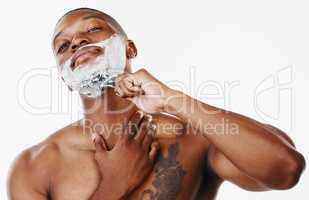 Too many days in a daze, better wake up. Studio shot of a handsome young man shaving his facial hair with a razor against a white background.