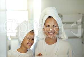 Playful mother and daughter doing a hygiene, skincare routine together in the bathroom. Mom teaching her adorable child a grooming and beauty treatment regime. Parent and little girl applying lotion