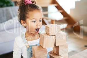 Theres magic to everything a kid sees. an adorable little girl looking surprised while playing with wooden blocks at home.