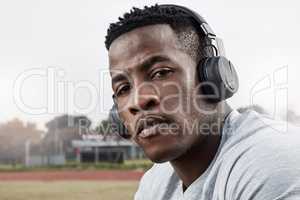 Turn up the volume and activate your beast mode. a sporty young man wearing his headphones while out for a workout.