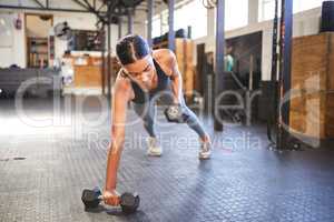 Nothing is too heavy for a strong will. a young woman working out with weights in a gym.