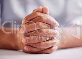 A man of faith. an unrecognizable man sitting down with his hands clasped in prayer.