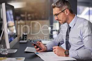 I know just the person to call. a businessman using his cellphone while sitting at his desk.