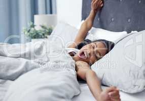 I still need a few minutes before I wake up properly. a young woman yawning and stretching while lying in her bed.