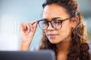 Making sure she doesnt miss a detail. an attractive young businesswoman working on her laptop in the office.