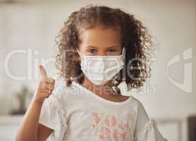 Girl with a covid face mask and thumbs up like sign showing she is wearing protection or caution against virus, One brave and responsible little child with good OK gesture or success emoji expression