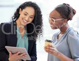 Technology is the third member of their team. two attractive young businesswomen looking a tablet while standing in the office.