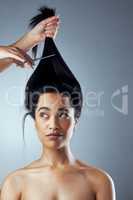 Time for the big cut. Studio shot of young woman getting her hair cut against a grey background.