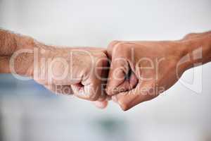 United in victory and success, achieving goals by working together as a community. Closeup of business men fist bumping hands in the office. Welcoming, promoting or supporting a colleague