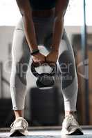 Shes got the kettle on. an unrecognizable and athletic young woman working out with a kettle bell in the gym.