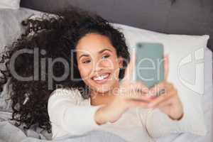 An early-morning selfie is a blessing for the whole day. a young woman laying in bed and using her mobile phone in the morning.