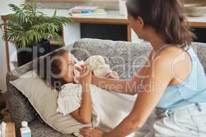Caring, loving and worried parent taking care of ill kid. Suffering from cold, flu or covid virus. Daughter, child and sick girl lying on sofa while mother helps her blow her nose in home living room