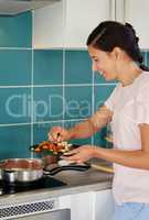 Its easier to add in than to take out. a young woman adding her raw vegetables to a dish.