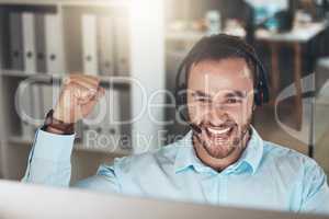 Yes Another issue resolved. a young call centre agent sitting alone in his office and celebrating a success while using his computer.