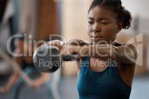 Lets get lifting. an attractive and athletic young woman working out with a kettle bell in the gym.