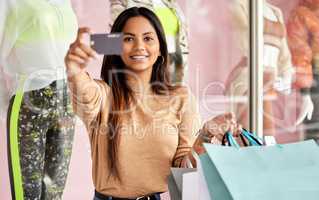My credit card can handle any price tag. Cropped portrait of an attractive young woman holding up a credit card while shopping in the city.
