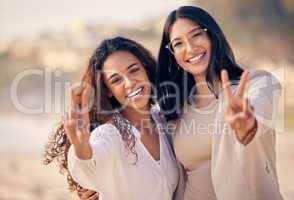 Friends come along and make the good times better. a woman showing the peace sign while outside with her friend.