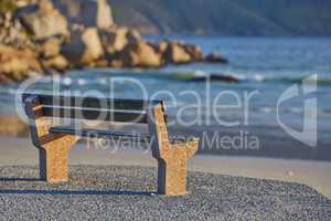 Relaxing bench with sea or ocean view to enjoy calm, peaceful and zen nature with waves washing on shore in a remote area. Scenic seating with blurred copy space in a coastal park on the promenade