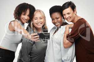 Say cheese, ladies. a diverse group of women standing close together in the studio and take a selfie with a cellphone.