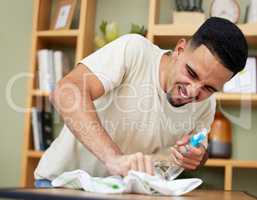 He doesnt mind putting in some effort. a young man cleaning a table at home.