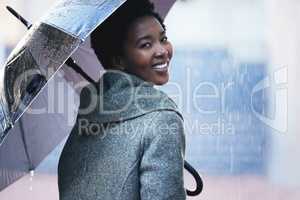 The best thing to do when it rains is to let it. a young businesswoman using an umbrella to cover with while going for a walk in the rain against an urban background.