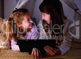 Should we do one more before bedtime. a little girl and her mother watching something on a digital tablet at night.