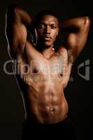 Muscle is good, confidence is even better. Studio shot of a fit young man posing against a black background.