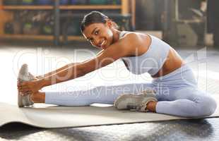 Its hard not to be happy when youre in good health. Portrait of a fit young woman stretching in a gym.