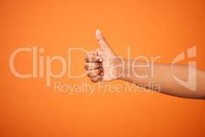 I approve of that. an unrecognizable person showing a thumbs up against an orange background.