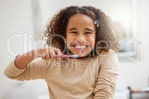 Encourage kids to develop positive hygiene habits. Portrait of an adorable little girl brushing her teeth in a bathroom at home.