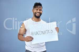 The vaccine is the right choice. a handsome young man standing alone in the studio and holding a poster after getting his Covid vaccine.