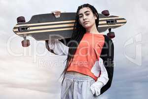 Always up for a skate. Cropped portrait of an attractive young female skater standing with her longboard against a stormy backdrop.