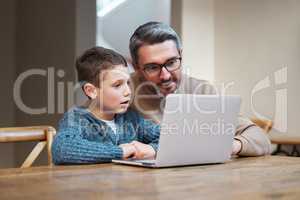 Teach your children the meaning of dedication. a father and son team using a laptop to complete school work.