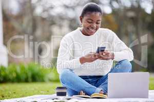 Learning is so much easier with all this technology. a young woman using a smartphone and laptop on the grass at college.