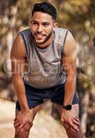 Taking a moment before going at it again. a handsome young man taking a moment to catch his breath during his outdoor run.