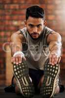 Get ready, things are about to get sweaty. a young man stretching before his workout in the gym.