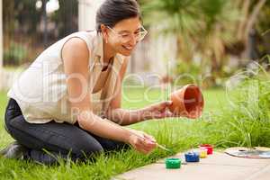 Creativity is just connecting things. s young woman painting a pot in the garden at home.