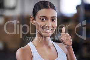 Keep on becoming strong. Portrait of a sporty young woman showing thumbs up in a gym.