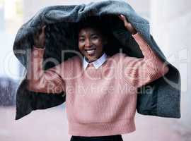 No umbrella, no problem. a young businesswoman using a jacket to cover with while going for a walk in the rain against an urban background.