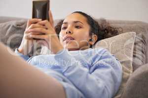 Music and relaxation. an attractive young woman listening to music and texting while relaxing at home.