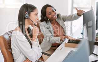 Allow me to explain. an attractive mature call center agent wearing a headset and helping a colleague while working in the office.