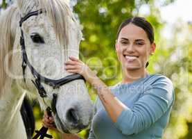 Pampering her horse. an attractive young woman standing with her horse in a forest.