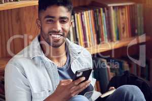 Tech that takes you to a higher level of learning. a young man using a smartphone in a library at university.