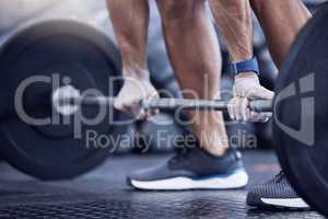 One more lift for the road. an unrecognisable man working out with a barbell at the gym.